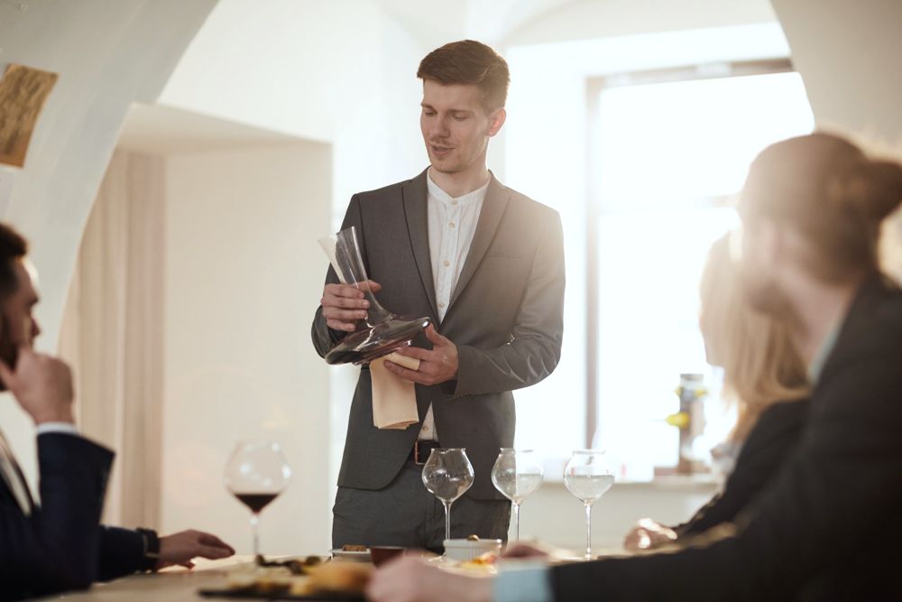 A host presenting wine to guests at a private tasting