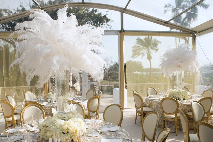 Clear tent dinner with white feather centerpieces and gold chairs