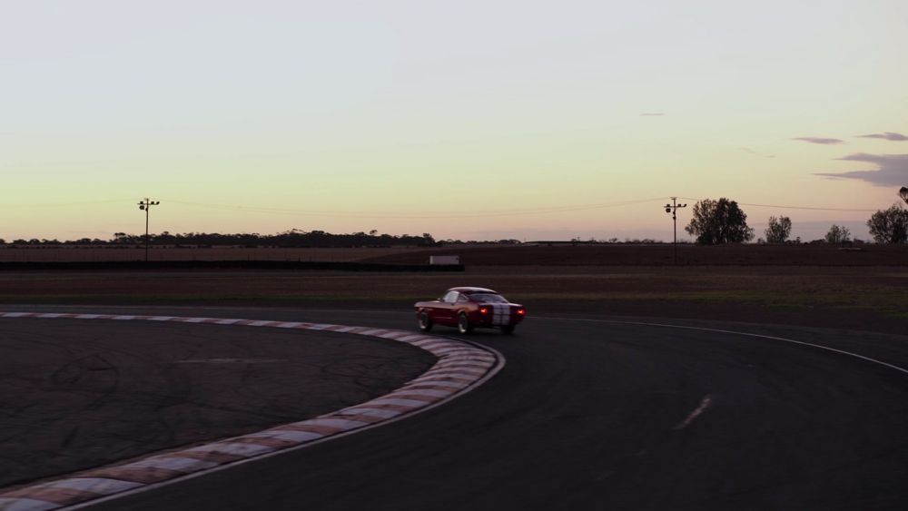 A sports car taking a corner on a race track at sunset